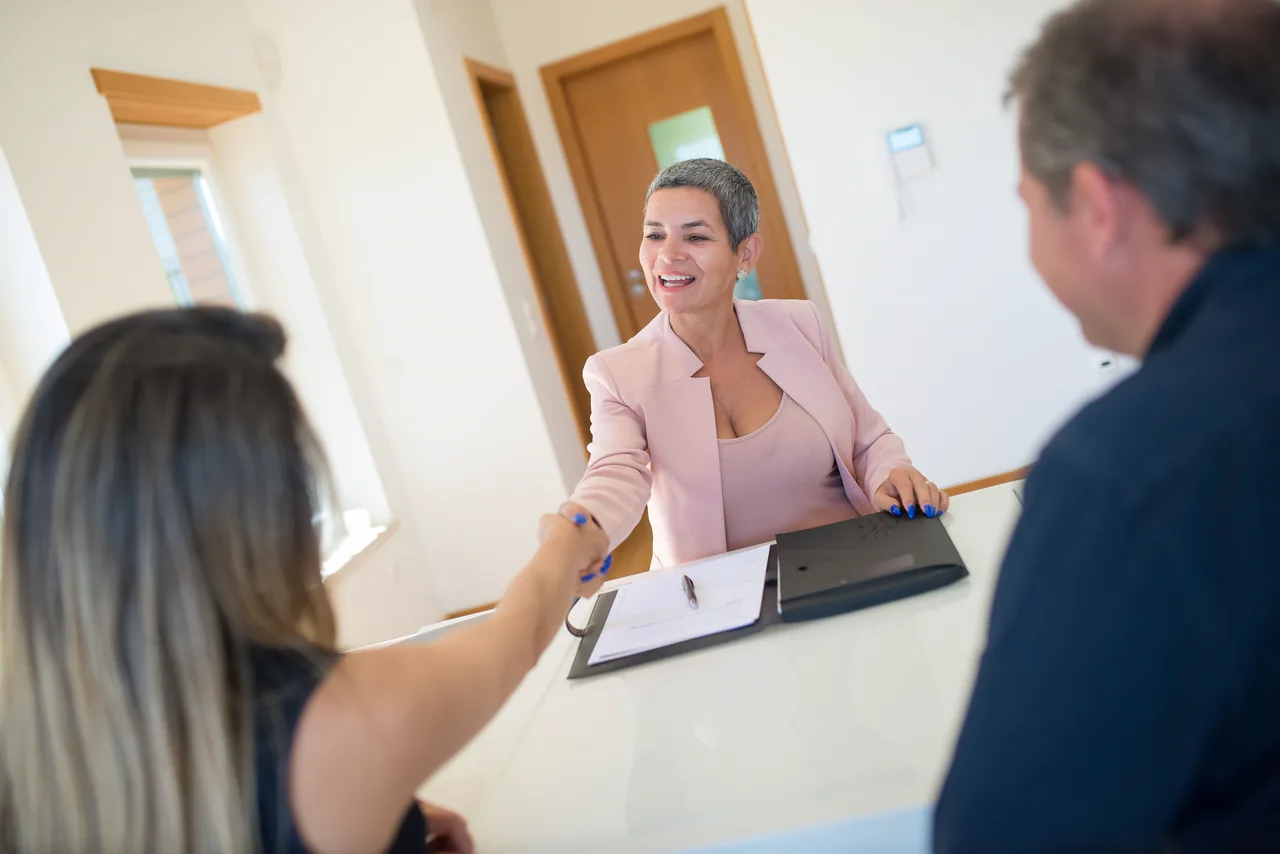 A smiling attorney shaking hands with a client across her desk